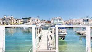 Un puerto deportivo con barcos amarrados, un muelle de madera y edificios frente al agua.