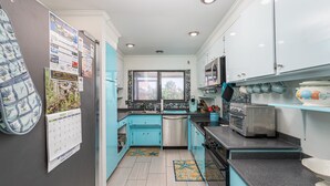 Une cuisine avec des armoires de couleur turquoise, un lave-vaisselle en acier inoxydable et un grille-pain vintage.