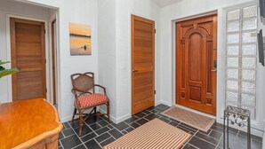 Un couloir avec des portes en bois, une chaise, un tapis et une petite table.