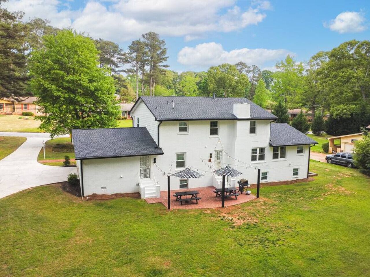 A two-story house with a patio area, a driveway, and a lawn.