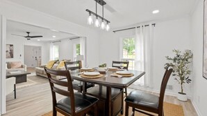Un comedor con una mesa de madera oscura, cuatro sillas y una lámpara de araña moderna.
