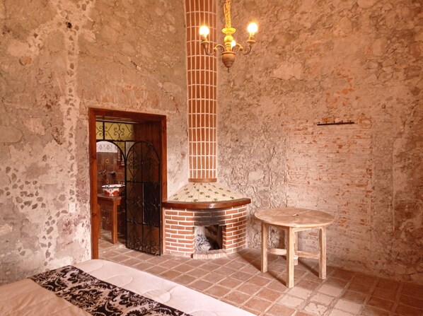 Una habitación rústica con chimenea de ladrillo, una puerta de madera y una pequeña mesa redonda.