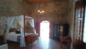 A room with a four-poster bed, a wooden dresser, a small table, and a mirror. - Hacienda Santiago Texmelucan (Oriental)