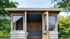 A small wooden cabin with a bed, a window, and a door. - Bogrie Country Cottage (Annan, Dumfries)