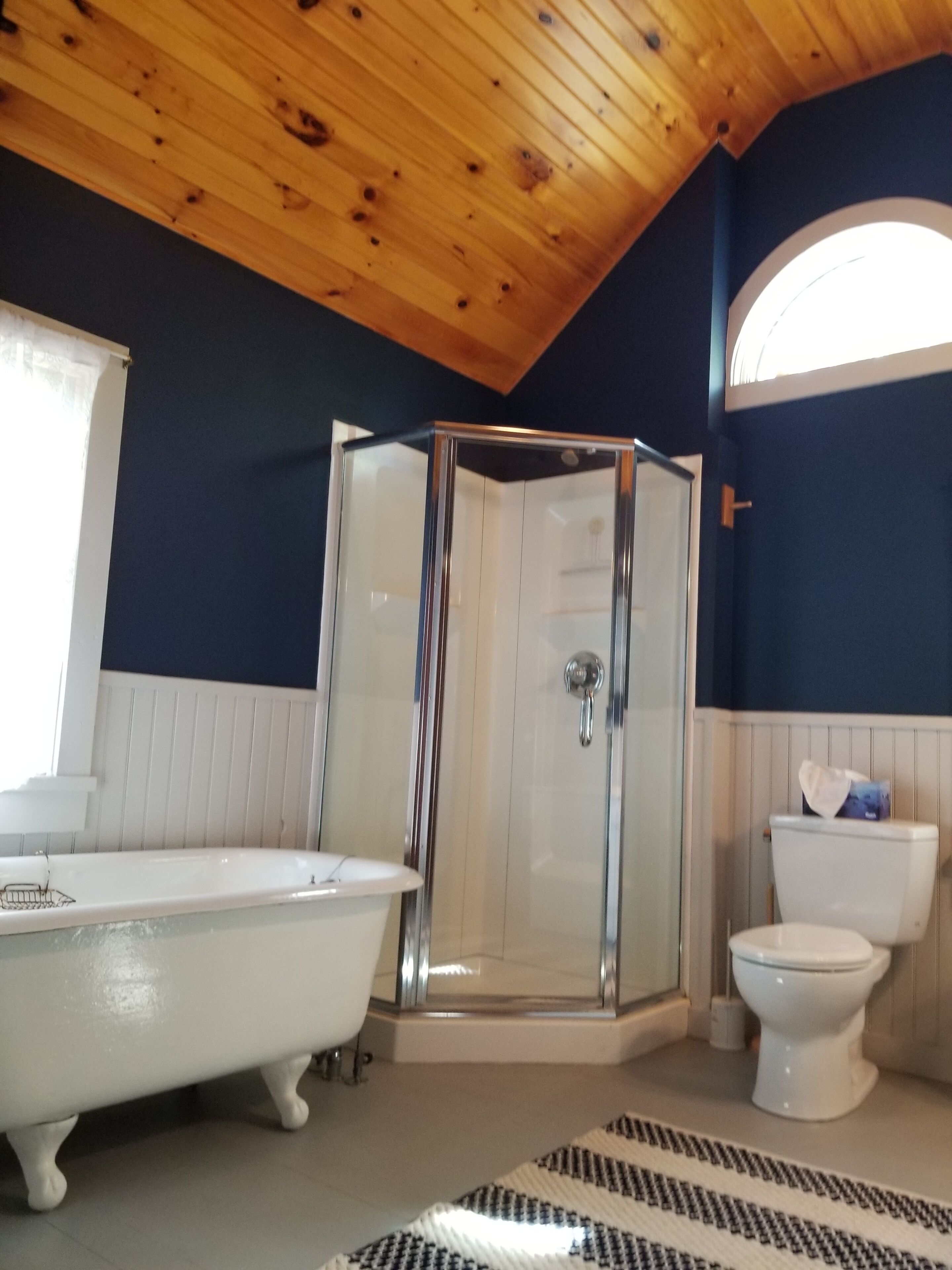 A bathroom with a glass-enclosed shower, a white bathtub, and a toilet.