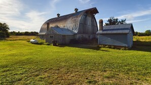 A rustic barn with a large, curved roof and a smaller attached structure. - 20 Minutes to Munising, Quiet Country Setting (Eben Junction)