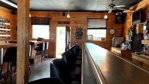 A bar area with wooden walls, a long counter, and bar stools. - 20 Minutes to Munising, Quiet Country Setting (Eben Junction)