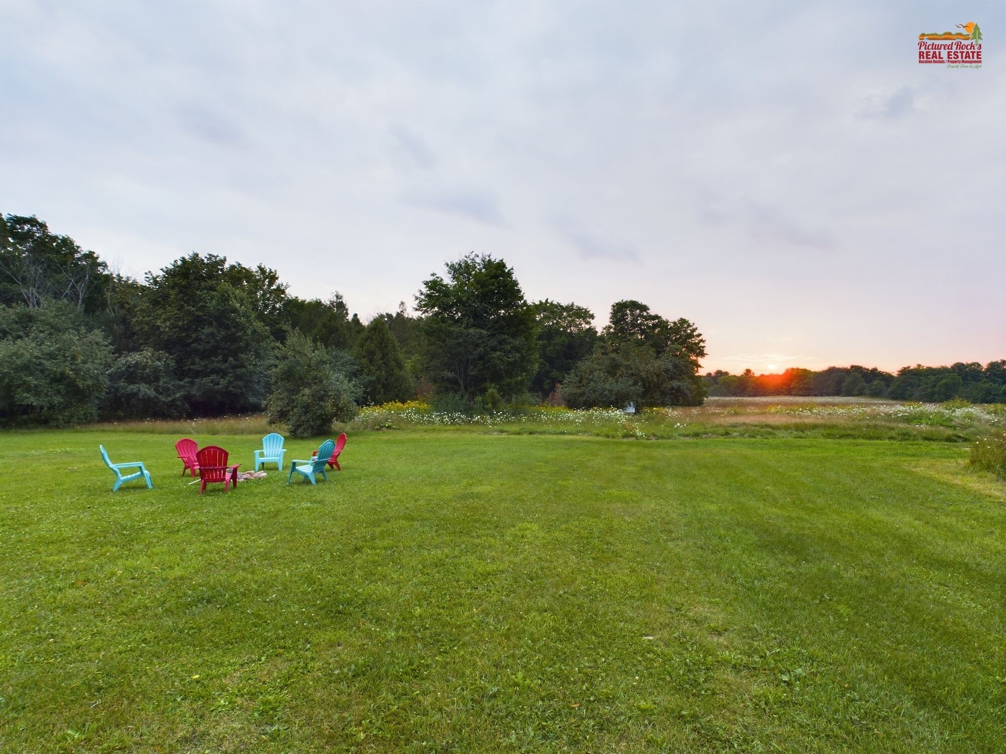A grassy outdoor area with several Adirondack chairs.