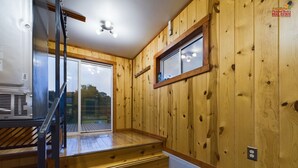 A wooden interior with a staircase leading to a balcony, a window, and a ceiling fan. - 20 Minutes to Munising, Quiet Country Setting (Eben Junction)