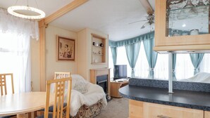 A cozy living room with a fireplace, a dining area with a round table and chairs, and a kitchen with a countertop and cabinets.