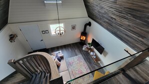 A loft-style room with a wooden staircase, a fireplace, and a large window. - Relaxing retreat in the country (perth east)