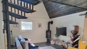 A cozy living room with a staircase, a fireplace, a sofa, a coffee table, a TV, and a bookshelf. - Relaxing retreat in the country (perth east)
