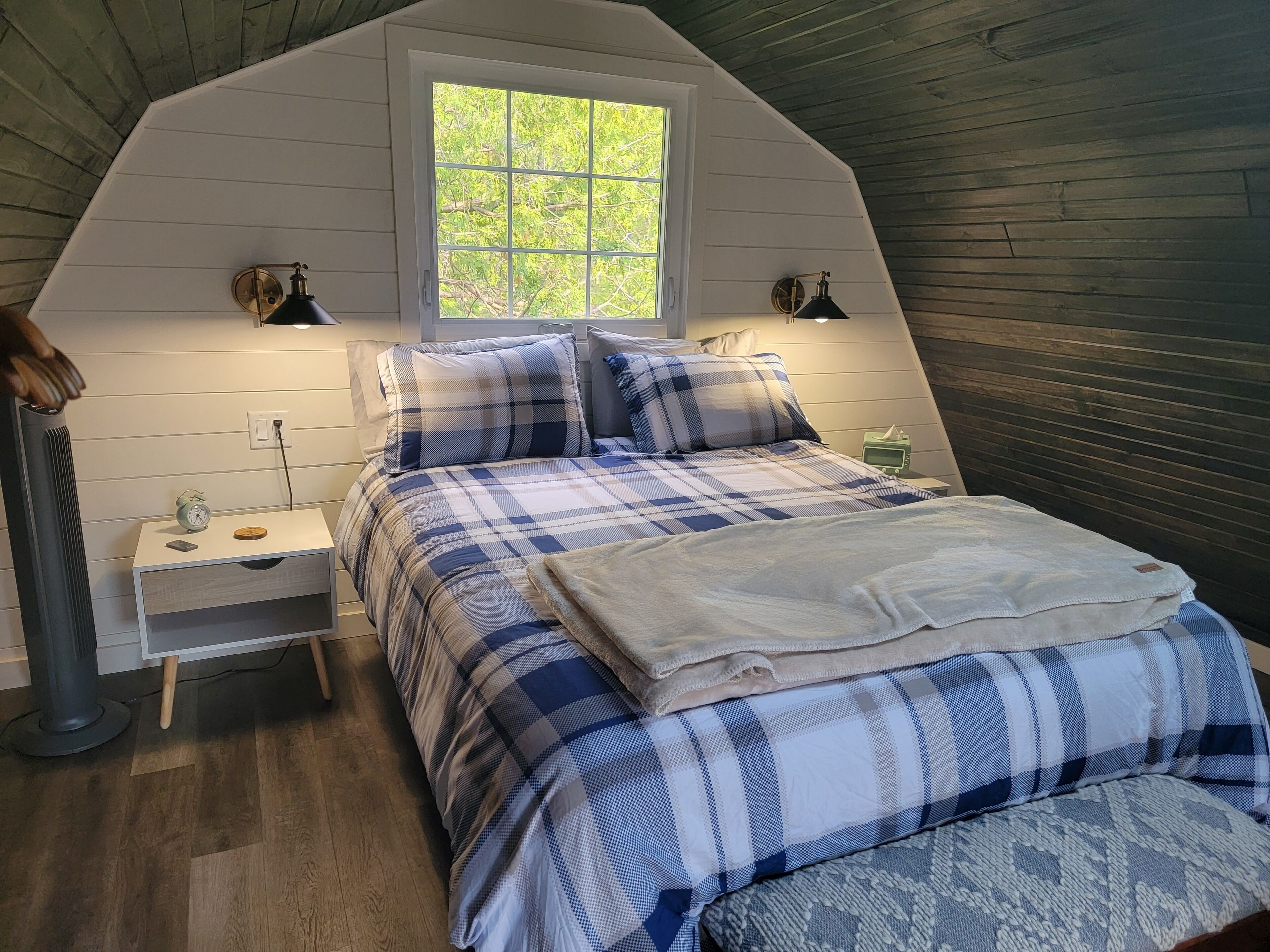 Un dormitorio con una cama, mesitas de noche, una ventana y un calentador.