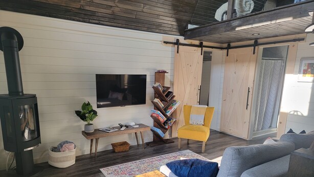 A cozy living room with a fireplace, a sofa, a coffee table, and a bookshelf. - Relaxing retreat in the country (perth east)