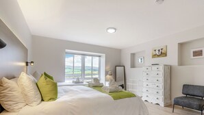 A bedroom with a large bed, a dresser, a chair, and a window with a view. - A fabulous place to come and make memories whatever the occasion. (Stanhope)
