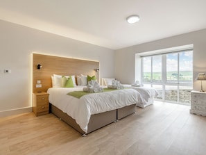 A modern bedroom with a large bed, bedside tables, a nightstand, a window with a view, and a ceiling light.