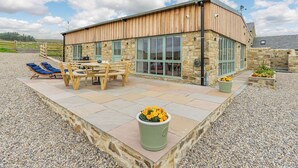 A modern building with a stone facade, large windows, and outdoor seating area with tables and chairs. - A fabulous place to come and make memories whatever the occasion. (Stanhope)