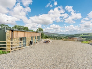 A building with a stone facade, a gravel patio, and a view of the countryside.
