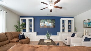 A living room with a brown leather sofa, a white armchair, a wooden coffee table, and a ceiling fan. - Stunning 5 BD Home away from Home! 15 min to uptown (Charlotte)