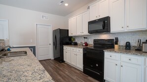 A modern kitchen with white cabinets, a black refrigerator, a microwave, and a stove. - Stunning 5 BD Home away from Home! 15 min to uptown (Charlotte)