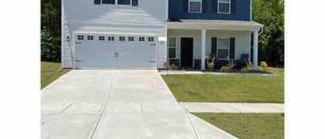 A two-story house with a garage, a front porch, and a well-maintained lawn.