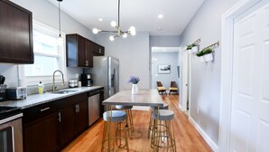 Cocina moderna con alacenas de madera oscura, un refrigerador de acero inoxidable y una zona de asientos con taburetes de bar.