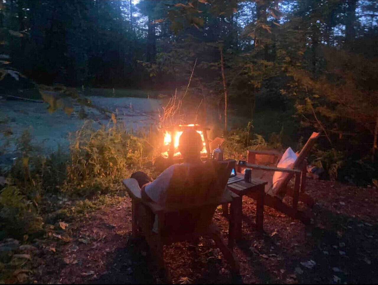 A campsite with a campfire, a table, and chairs.