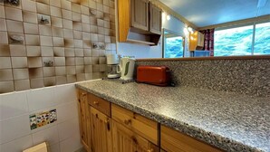 Eine Küche mit einer Granitabdeckung, Holzschränken, einem roten Toaster und einer Uhr an der Wand.