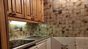 Eine Küche mit Holzausstattung, einer Granit Arbeitsplatte, einem Geschirrspüler und einer gefliesten Rückwand mit dekorativen Kacheln.