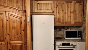 Eine Küche mit Holzausstattung, einem Bosch-Kühlschrank, einer Mikrowelle und einem Backofen.