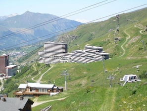 A hotel with multiple buildings, a ski lift, and a mountainous backdrop. - 10m from ski slopes, 15th floor, balcony, tv, ski locker, 39m², Les Menuires (Les Menuires)