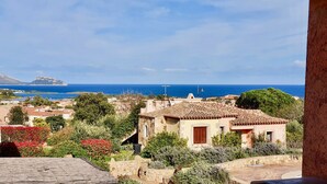 A coastal village with terracotta-roofed houses, a stone pathway, and a view of the sea and distant island. - Stunning Apartment With Pool in Olbia, Sardinia (Olbia)