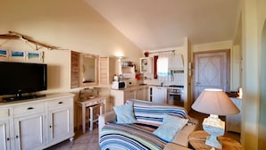 A compact living space with a TV, kitchenette, and a striped sofa. - Stunning Apartment With Pool in Olbia, Sardinia (Olbia)