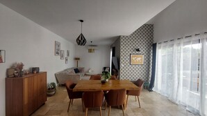Una sala de estar moderna con una mesa de comedor de madera, sillas marrones, un sofá y una pared decorativa con un mapa del mundo.