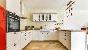 Una cocina moderna con armarios blancos, un horno rojo y piso de baldosas.