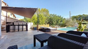 Un patio exterior con mobiliario de mimbre, una piscina y una terraza de madera.