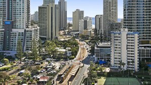 A high-rise urban area with modern buildings, a tram line, and a tennis court. - Ocean View 2-Bed Studio In the Heart of Surfers (Surfers Paradise)