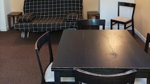 Ein Zimmer mit einem dunklen Holztisch und Stühlen, einem schwarz-weiß karierten Sofa und zwei kleinen Beistelltischen.