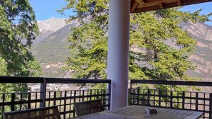 A wooden table and chairs under a covered patio with a mountain view. - Floor -2, view valley, swimming pool, hammam, terrace, parking, tv, 50m², Pra Loup (Jausiers)