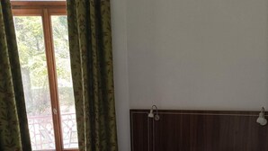 A bedroom with a wooden headboard, a white bedspread, and a view of a balcony through a window with green curtains. - 2nd floor, swimming pool, hammam, terrace, balcony, parking, tv, 55m², Pra Loup (Jausiers)