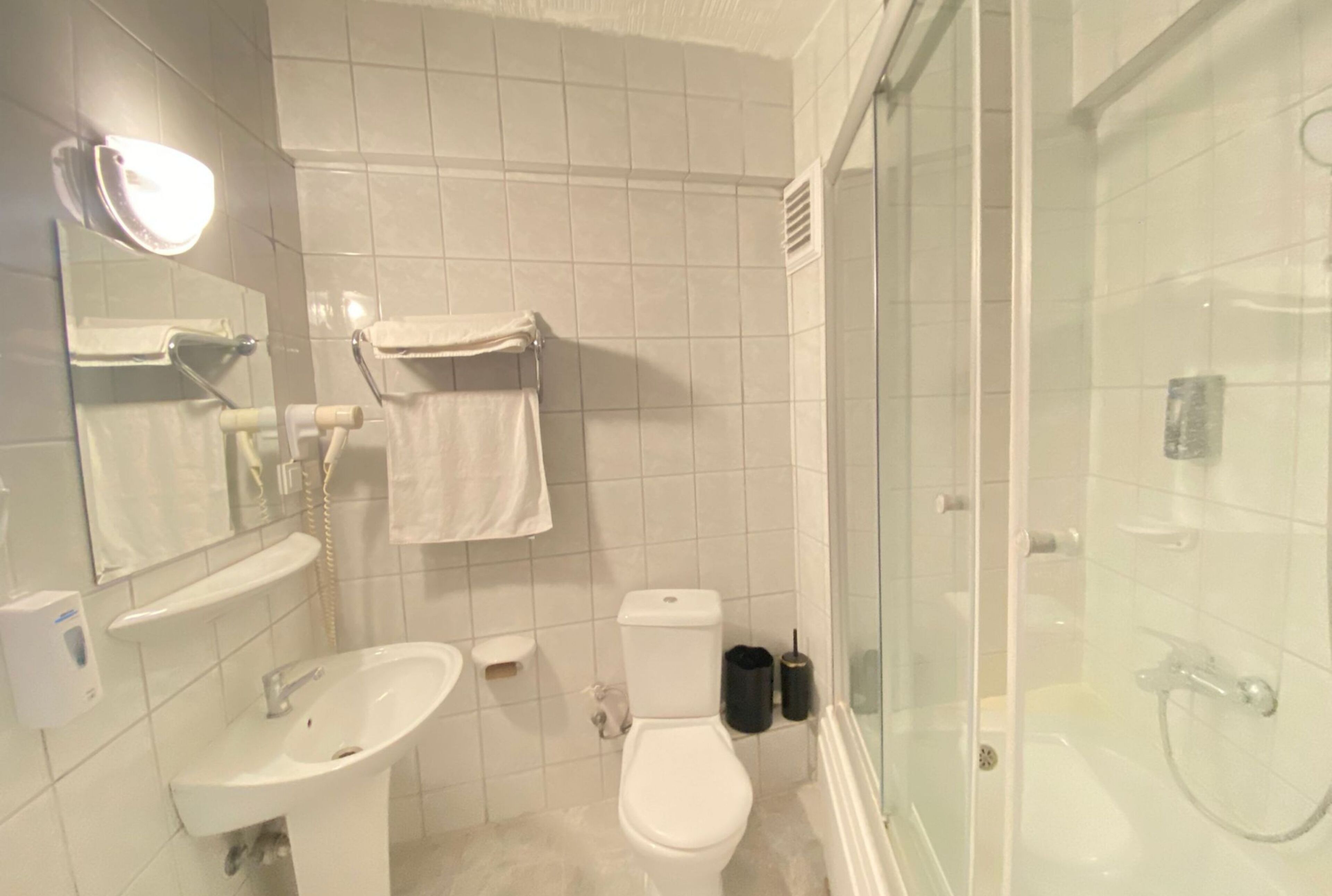 Un baño con inodoro, lavabo y zona de ducha con mampara de vidrio.