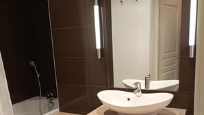 Een moderne badkamer met een groot wastafel, spiegel en douche.