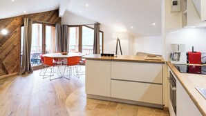 A modern kitchen with a central island, wooden flooring, and large windows. - Apartment with magnificent view in Le Hameau des Airelles (Montgenèvre)