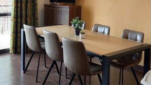 A dining area with a wooden table, six chairs, a television, a wall-mounted light, and a potted plant. - Floor -2, view valley, swimming pool, hammam, terrace, parking, tv, 50m², Pra Loup (Jausiers)