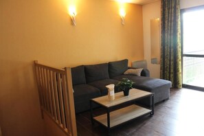 A living room with a sofa, a coffee table with a plant, and two wall-mounted lights. - Floor -2, view valley, swimming pool, hammam, terrace, parking, tv, 50m², Pra Loup (Jausiers)