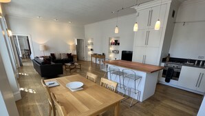 Une cuisine moderne avec des meubles blancs, une table à manger en bois et des tabourets de bar.