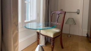 Une pièce avec une table en verre, une chaise en bois dotée d’un siège rembourré, une lampe et une porte avec une pancarte.