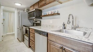 A modern kitchen with stainless steel appliances, wooden cabinets, and a granite countertop. - Institute Bliss! Newly Remodeled Family Home! (Colorado Springs)