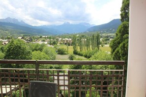 Un balcón con vistas a un valle, casas y montañas.