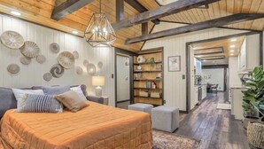 Un dormitorio con una cama grande, techo de madera y una estantería al fondo.